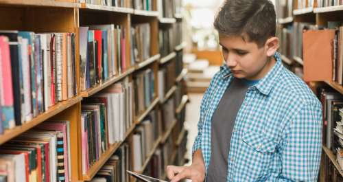 Jeune avec tablette dans une bibliothèque